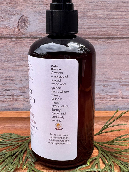 A bottle of cedar Blossom Lotion with cedar on a wooden board.