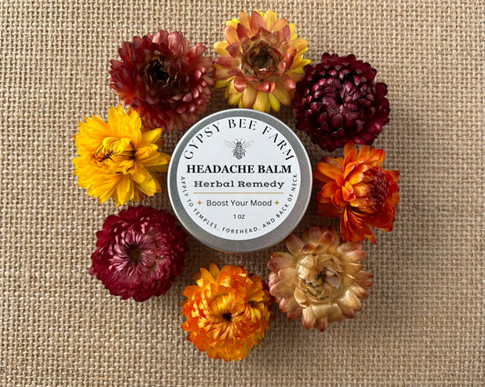 Headache balm container surrounded by colorful flowers on a textured fabric background