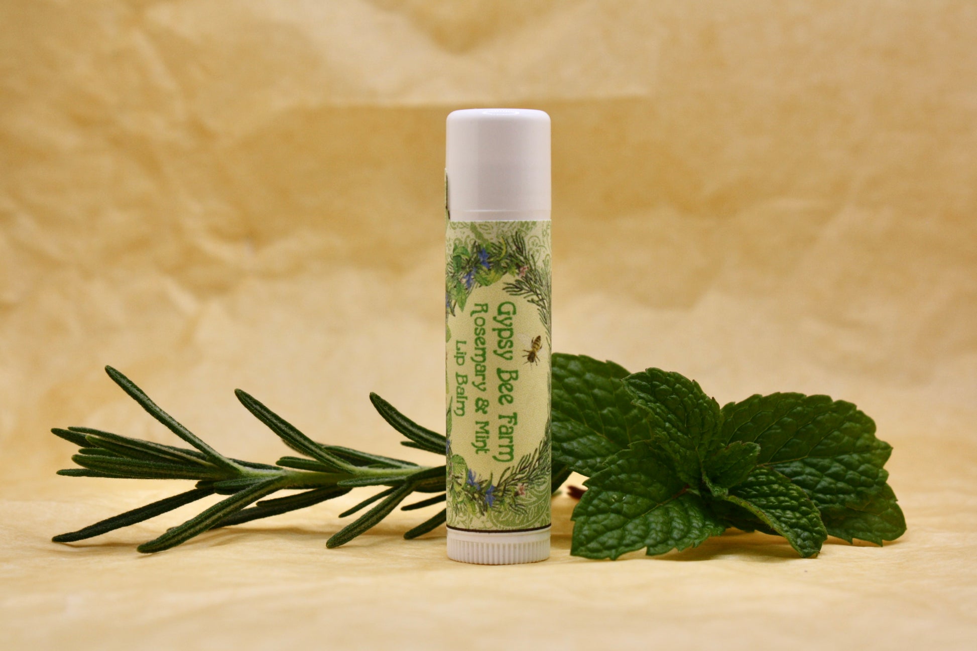 Lip balm with green label and mint leaves on a beige background