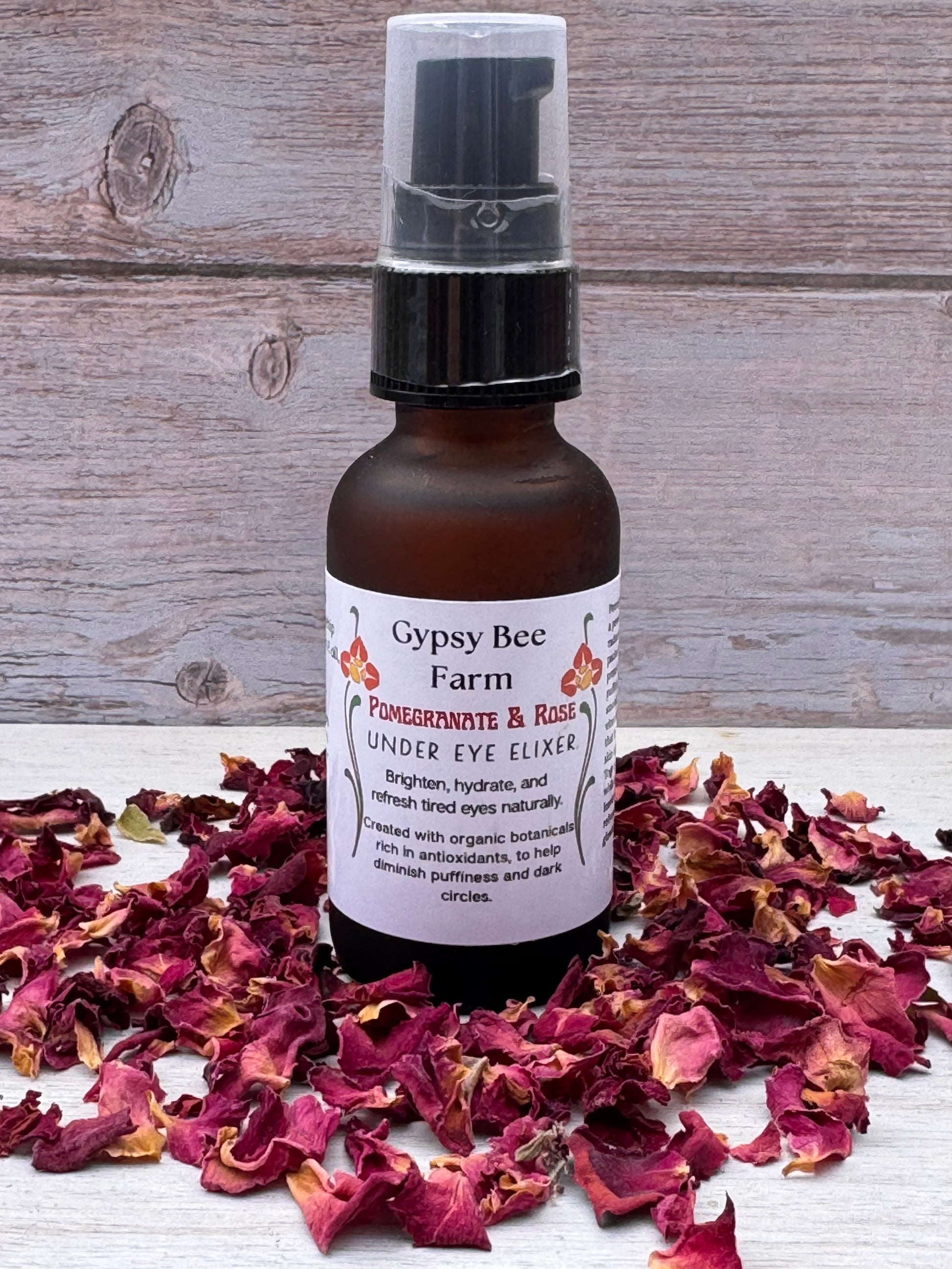 Bottle of Gypsy Bee Farm product surrounded by dried flowers on a wooden surface