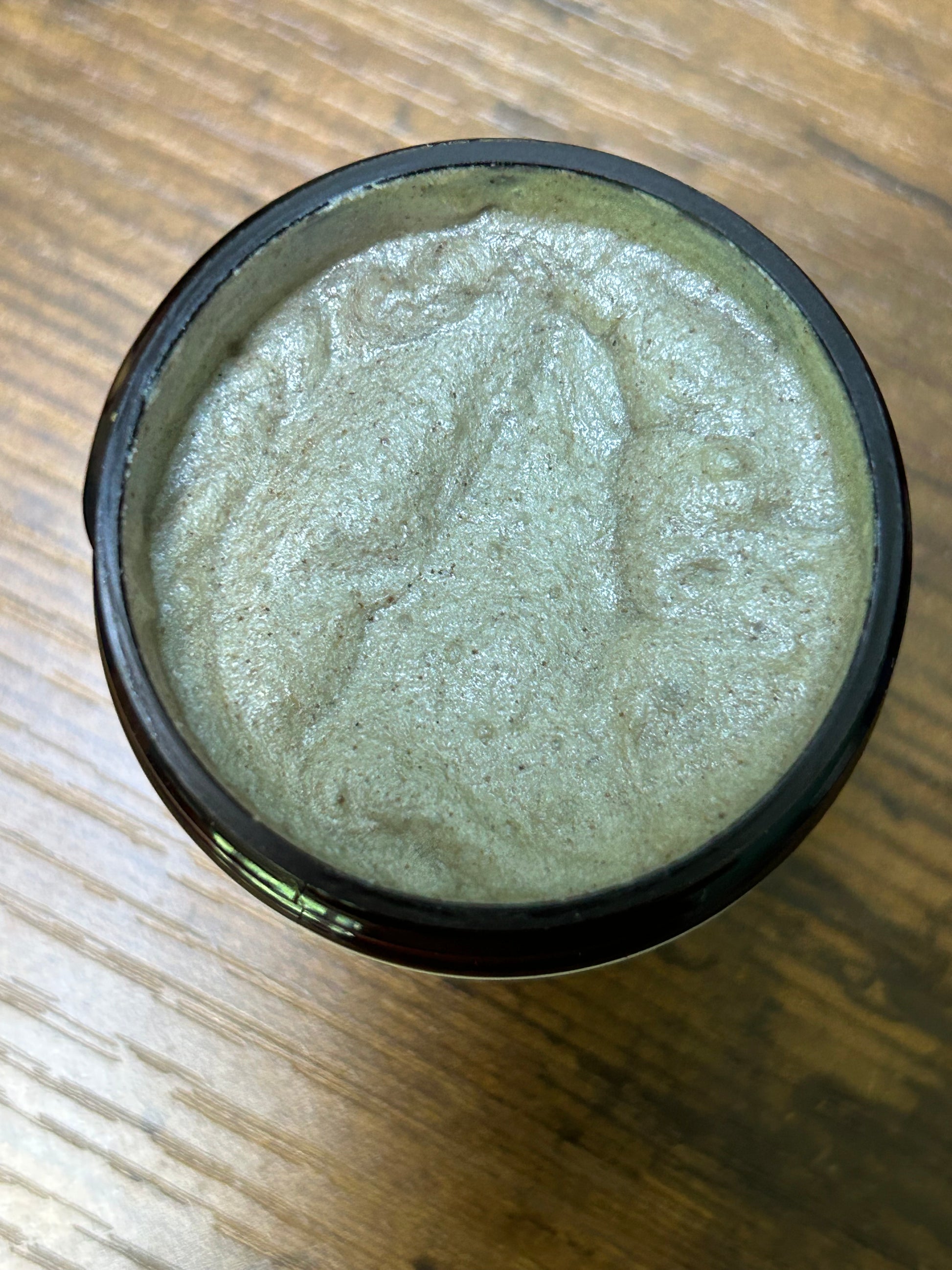 Green paste in a black container on a wooden surface