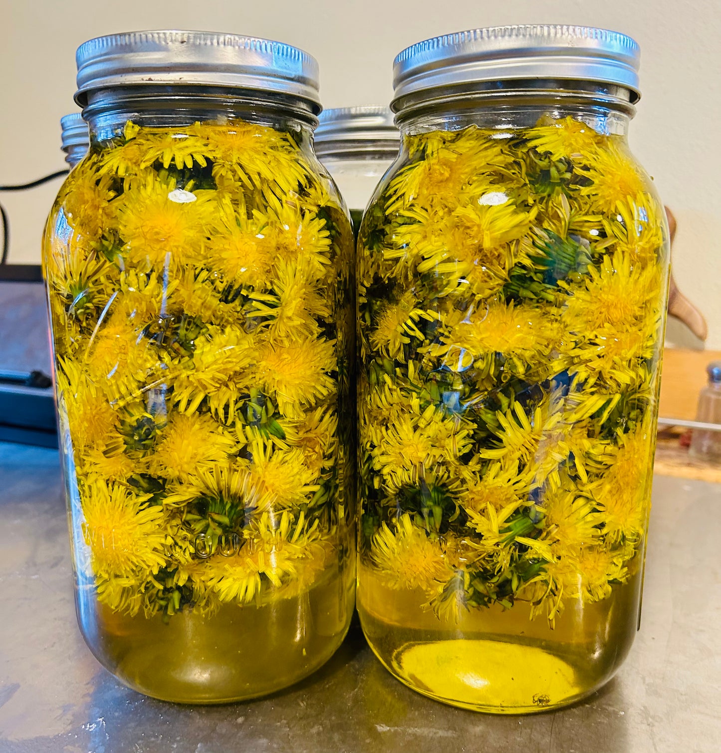 Two jars filled with yellow flowers on a countertop.