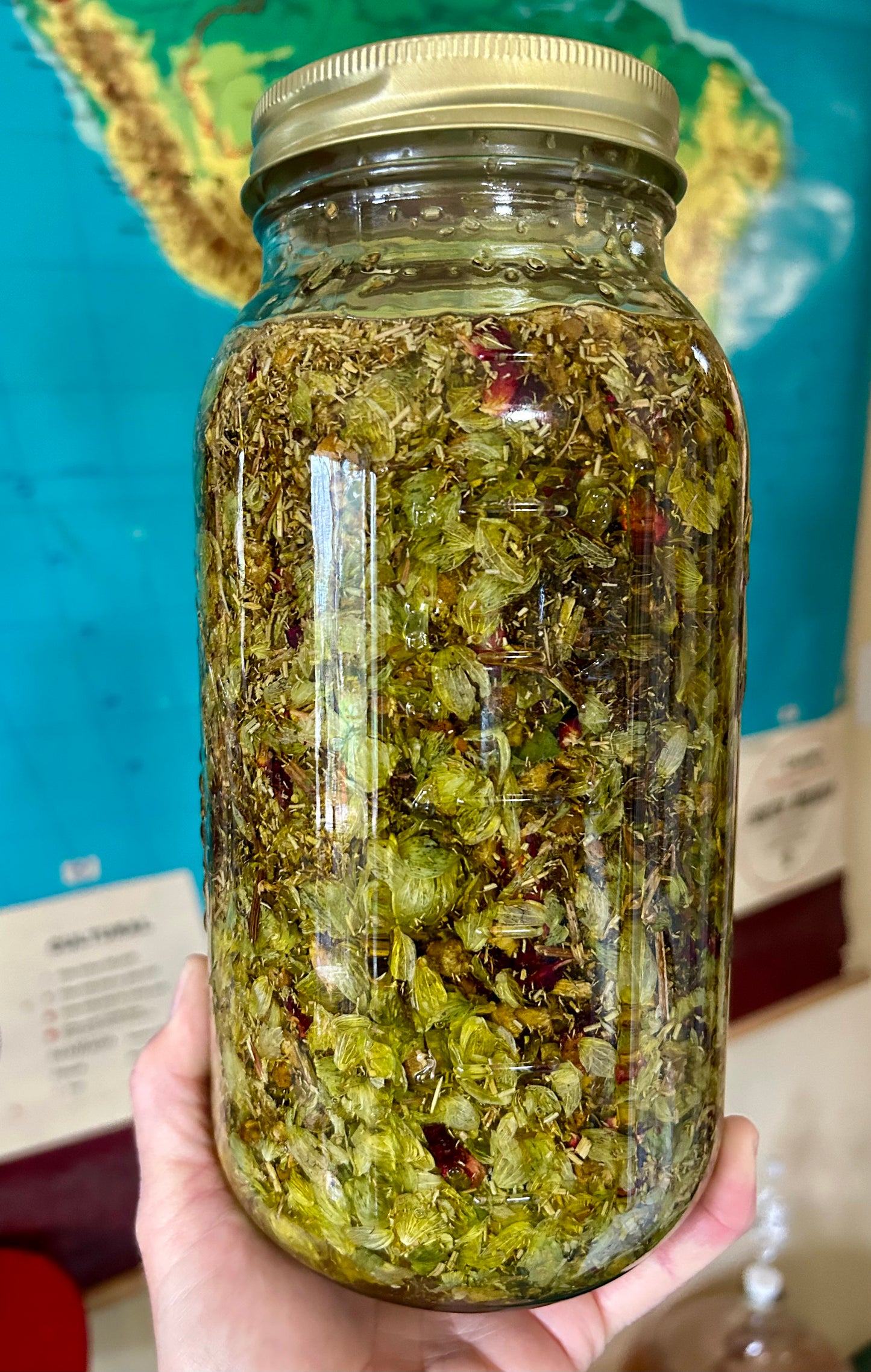 Glass jar filled with green herbal mixture held by a hand against a blurred background