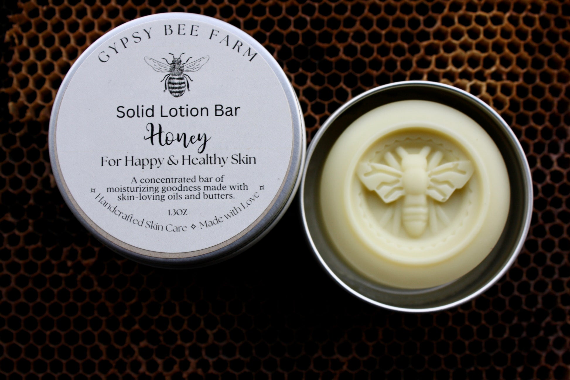 Gypsy Bee Farm solid lotion bar in a metal container on a honeycomb background