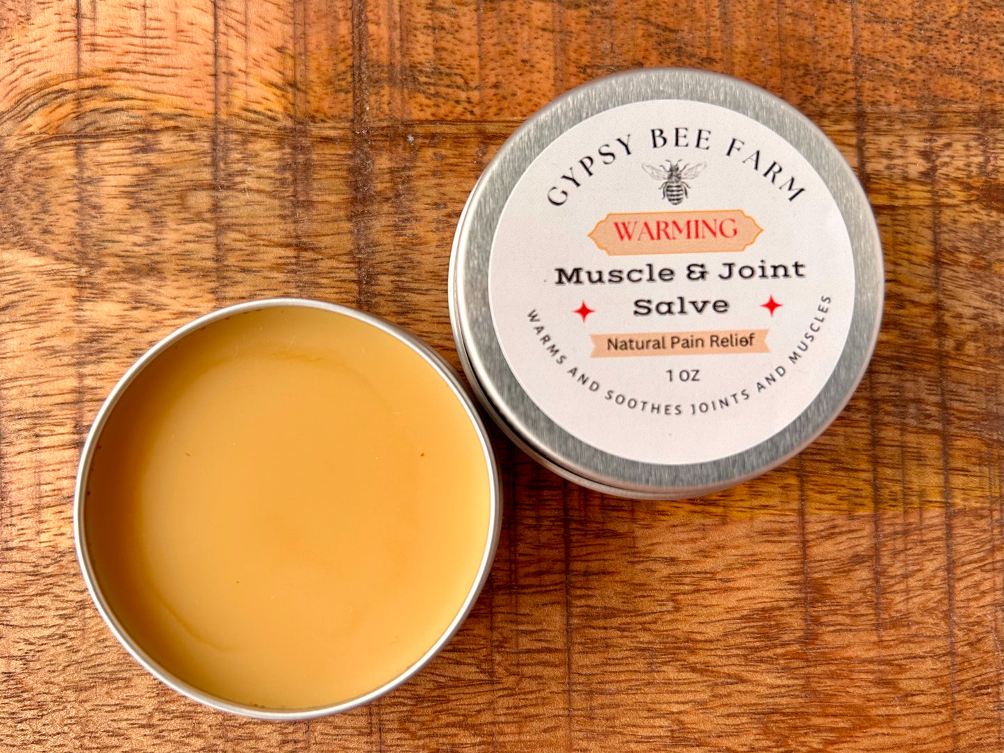 Gypsy Bee Farm Muscle & Joint Salve in a metal tin on a wooden surface