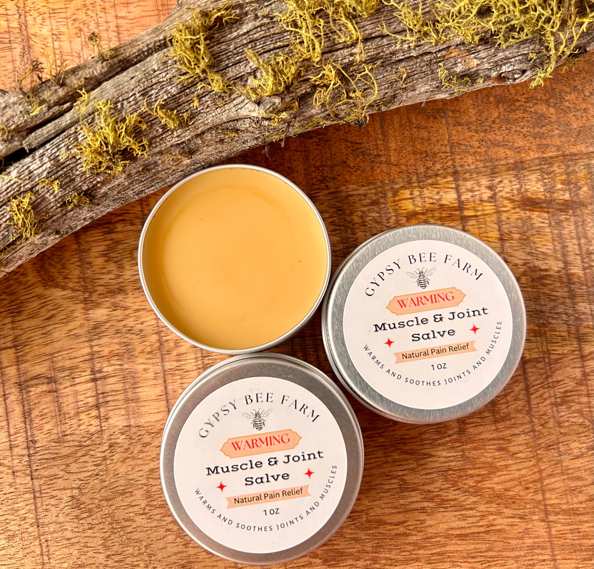Gypsy Bee Farm Muscle & Joint Salve tins on a wooden surface with a natural background.